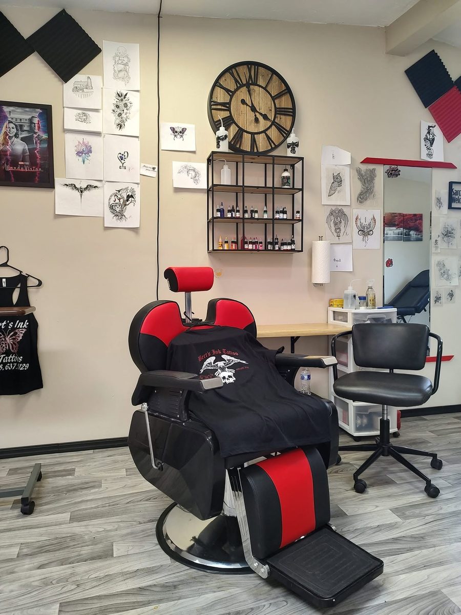 The chair at Bert's Ink, with drawings on the wall and the clock above