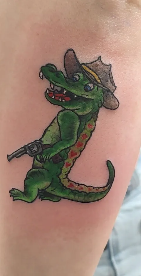Cartoon alligator in a cowboy hat with a pistol on the forearm, in color