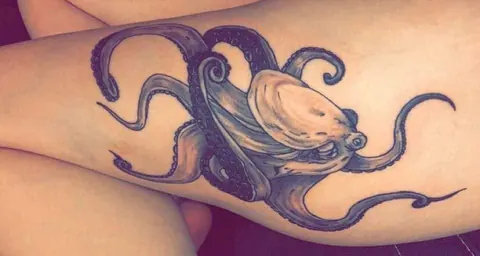 Octopus wrapping around the arm in purple and black