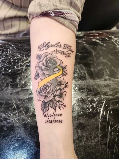 Roses with a name and dates in script on the forearm, black and gray