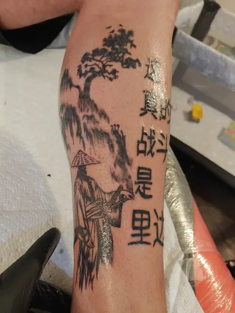 Samurai beneath a bonsai tree with lettering down the forearm, black and gray