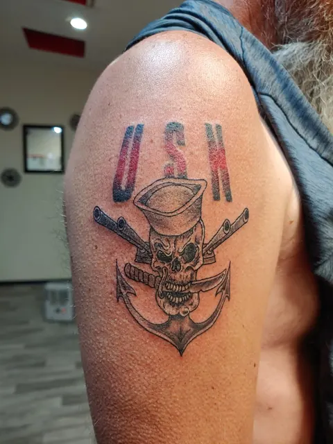 Skull in a sailor cap over an anchor with USA lettering on the upper arm